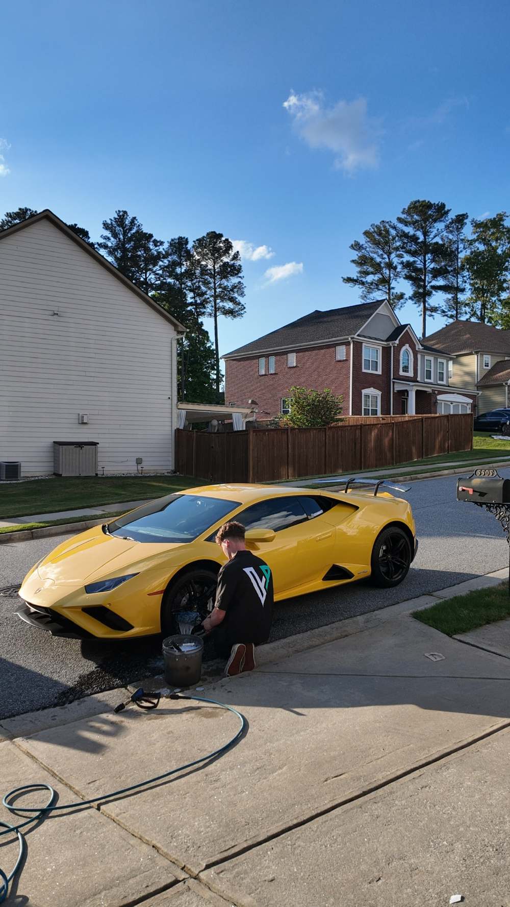 Detailer hand washing a yellow Lamborghini in an Atlanta driveway
